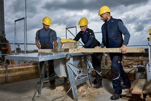 Trois couvreurs en tenue de travail sont à l'œuvre.